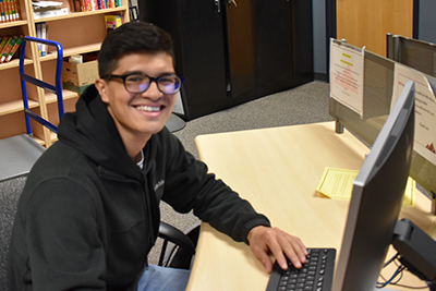 Gabriel Solis Ramos sitting at a computer in the LRC at WCC at the Crossroads Institute in Galax